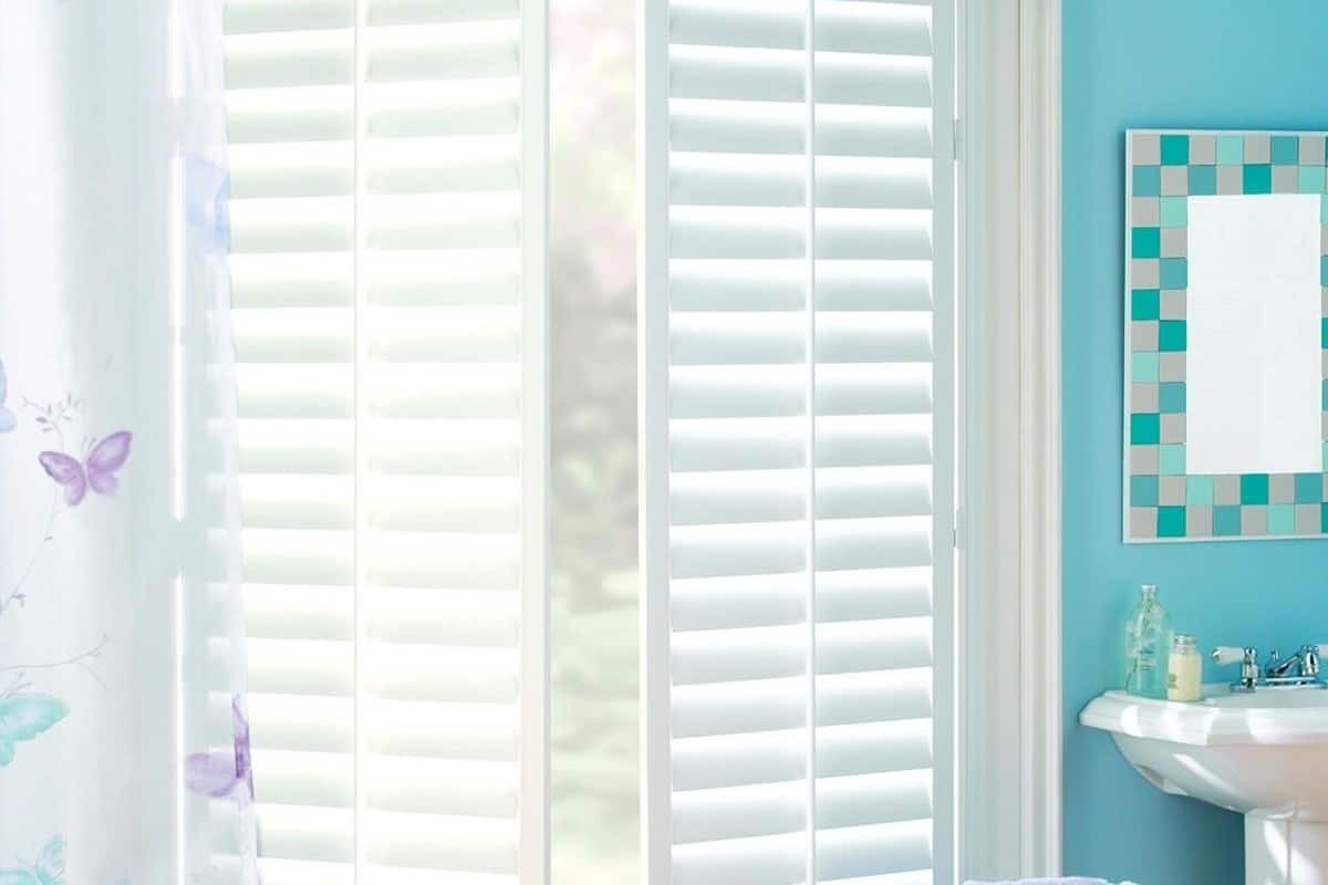 Hunter Douglas Palm Beach™  Polysatin™ Vinyl shutters in a bathroom with light filtering in.